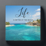 Beach Saying Tropical Beach with Thatched Huts Plaque<br><div class="desc">A photo plaque which says: Life is better at the beach. Designed with a beautiful photo featuring a tropical beach resort. 
Pretty blue water and white sandy beach with thatched huts giving it a tranquil island vibe.</div>