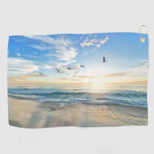 Beach with birds flying over the water Towels