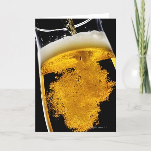Beer been poured into glass studio shot card