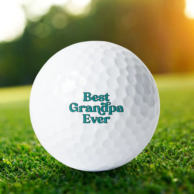 A golf ball for a grandfather is lying on a patch of grass. The sun is shining in the background. 