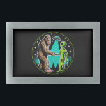Bigfoot Alien Alliance - Funny Scifi Cryptid Belt Buckle<br><div class="desc">Step into a world where the extraordinary meets the unexplained with this captivating design. At its heart, a legendary Bigfoot extends a friendly hand to an alien, both bathed in the ethereal glow of a UFO’s beam. Set against a backdrop of a serene pine forest under a star-studded night sky,...</div>