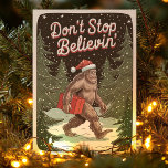 Bigfoot Don't Stop Believin Sasquatch Christmas Holiday Card<br><div class="desc">Add some mythical charm to the holidays with this funny Bigfoot holiday card! Featuring a festive Sasquatch in a Santa hat carrying a gift through a snowy forest, this "Don't Stop Believin'" card is perfect for those who love a touch of whimsy. Ideal for friends, family, or anyone who enjoys...</div>