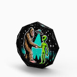 Bigfoot Meets Alien Acrylic Award<br><div class="desc">This whimsical image illustrates a friendly encounter between two legendary beings: Bigfoot and an alien. The scene, set against a starry night sky with silhouettes of pine trees, shows Bigfoot and the alien shaking hands under the beam of a UFO hovering above. Bigfoot, covered in brown fur, stands on the...</div>
