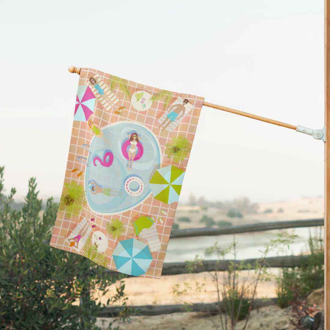A printed house flag hanging from a natural wood pole with a sandy landscape and muted sky in the background. The flag design offers an overhead perspective of a lively pool scene set against a peach and white tile grid, featuring illustrated figures swimming and lounging, a pink flamingo float, a ring float, striped deck chairs, tropical foliage, and boldly colored pinwheel umbrellas in pink, lime green, and sky blue.