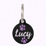 Black and Lavender Pet Paws and Custom Name Lucy Pet ID Tag<br><div class="desc">Ensure the safety and style of your beloved pet with this personalized pet ID tag. The sleek black tag features two lavender purple paw prints on the front, adding a touch of charm to your furry friend's collar. The custom name, such as Lucy, is elegantly printed in a lovely cursive...</div>
