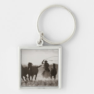 Black and White photo of a Cowboy Lassoing Horses Keychain
