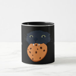 black cat holding a cookie in its teeth mug