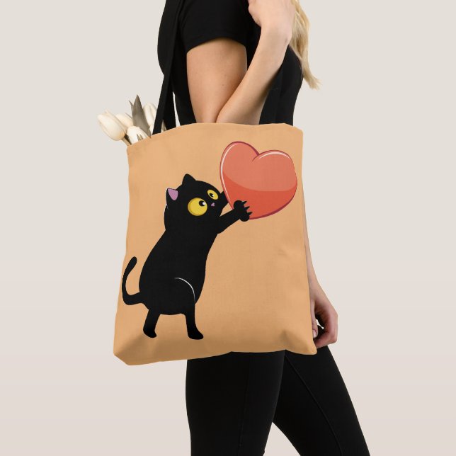 Black cat holding heart tote bag (Close Up)