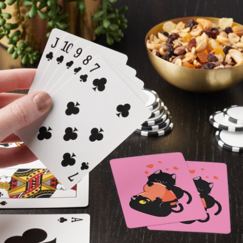 Black cats play with heart playing cards