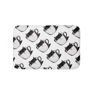 Black kitten with red nose hiding in a cup bath mat
