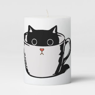 Black kitten with red nose hiding in a cup pillar candle