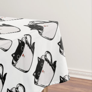 Black kitten with red nose hiding in a cup tablecloth