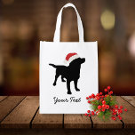 Black Lab Dog with Christmas Santa Hat Reusable Grocery Bag<br><div class="desc">This adorable black lab dog design features a black labrador retriever silhouette wearing a red and white christmas santa hat. Personalize with your own text - your name, christmas greetings, your dog's name, etc. This makes a cute, festive design for Christmas or winter holidays. Change the background color by clicking...</div>