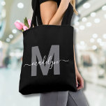 Black Trendy Modern Script Name Monogram Tote Bag<br><div class="desc">Personalized Elegant Black Trendy Modern Script Name Monogram Tote Bag. Add a touch of sophistication to your everyday style with this chic tote bag. Featuring a sleek gray initial centered on a crisp black background, with a clean and modern design on both sides, this tote combines elegance with practicality. Perfect...</div>