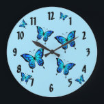 Blue Butterflies Wall Clock<br><div class="desc">This wall clock features beautiful morpho butterflies.  These tropical butterflies are among the largest in the world.  Their wings are a vivid iridescent blue. You can easily personalize or remove the name.</div>