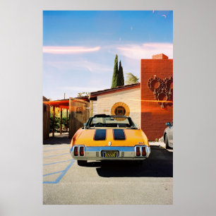 Blue car parked beside brown concrete building in poster