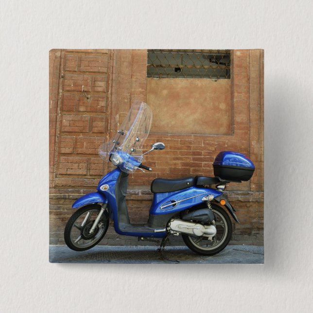 Blue motor scooter by red wall, Siena, Italy Button (Front)