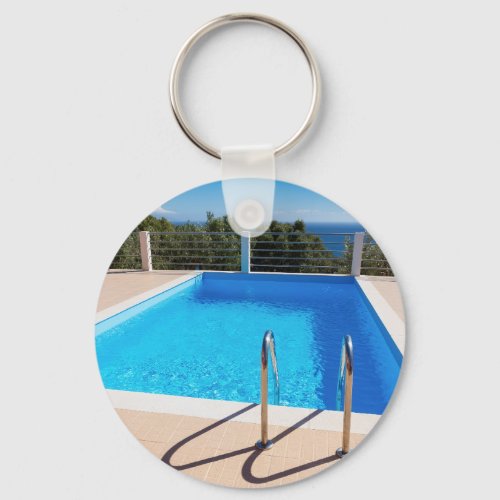 Blue swimming pool with steps at sea keychain
