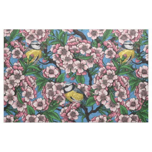 Blue tit birds in the blooming cherry tree on blue fabric