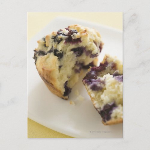 Blueberry muffin split open on a white plate postcard