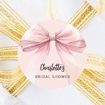 Bow pink Bridal Shower Classic Round Sticker<br><div class="desc">A blush pink colored background. Decorated with a large bow.  Personalize and add the bride's name. Black handwritten style script.</div>