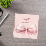 Bridesmaid blush pink bow notebook<br><div class="desc">A blush pink background color. Decorated with a large pink bow.  Personalize and add your bridesmaid's name.  Golden handwritten style script.</div>