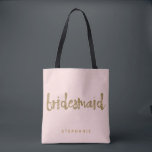 Bridesmaid Gold Glitter Blush PInk Tote Bag<br><div class="desc">This Bridesmaid tote bag is perfect for busy bridesmaids to tote around all their belongings at the bridal shower or the main event. This blush pink tote bag features faux gold glitter style lettering on the front. Personalize these totes with your wedding party member's name on the front and the...</div>