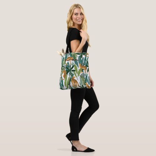 Brown leopard in tropical lush jungle leaves  tote bag