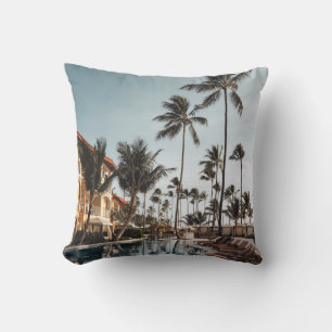 Brown wooden lounge chairs near pool surrounded by throw pillow