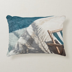 Brown wooden lounger near body of water accent pillow