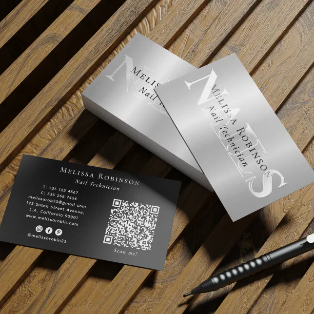 A silver spot UV business card is lying on a wooden bench with a pen next to it.