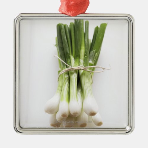 Bunch of spring onions on white chopping board metal ornament