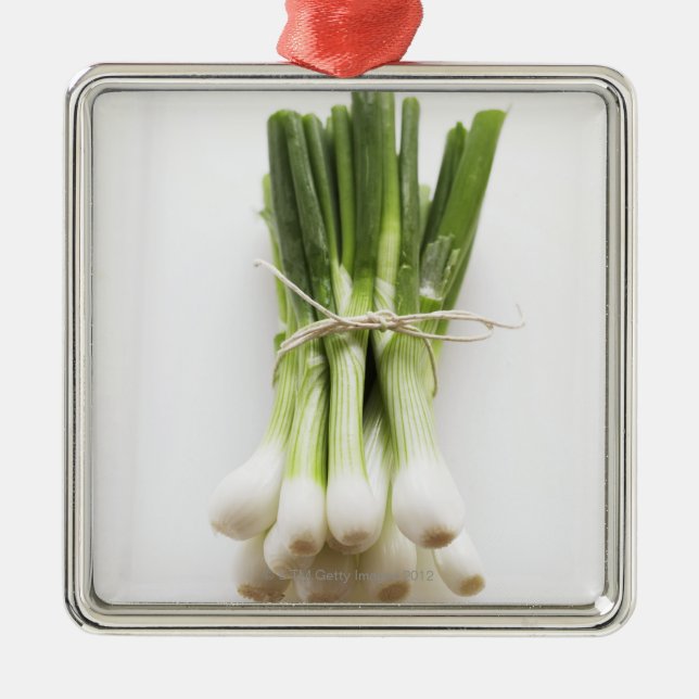 Bunch of spring onions on white chopping board metal ornament (Front)