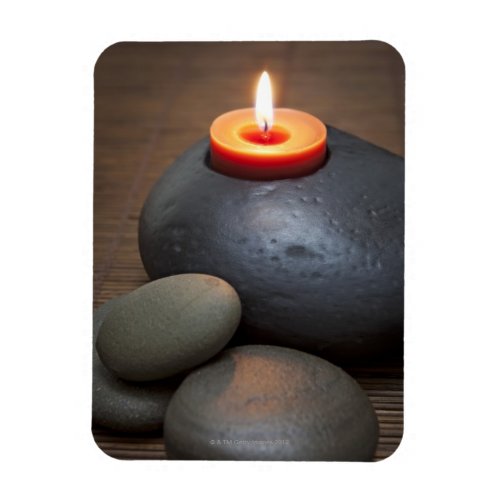 Burning candle flame with rocks in tranquil magnet