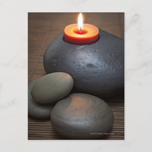 Burning candle flame with rocks in tranquil postcard