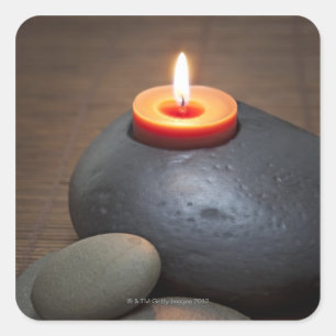 Burning candle flame with rocks in tranquil square sticker