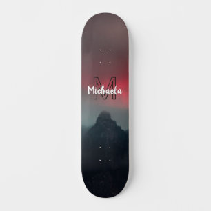 Burning clouds, fog and mountains monogram in sky skateboard