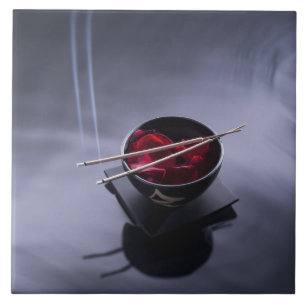 Burning incense on top of bowl of petals ceramic tile