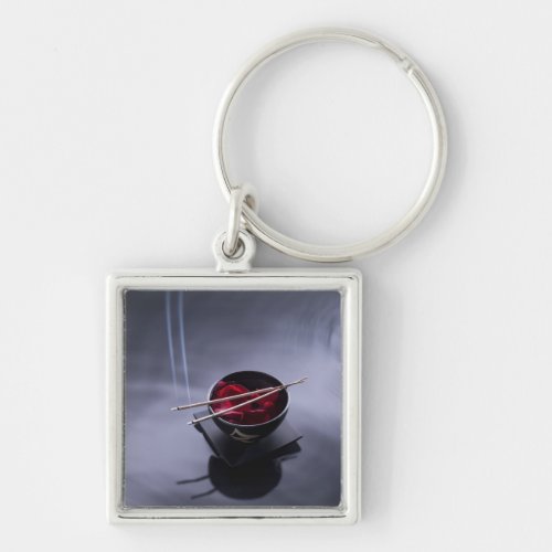 Burning incense on top of bowl of petals keychain