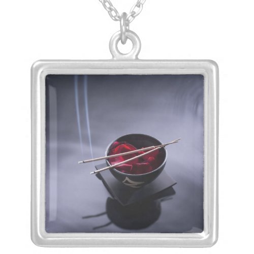 Burning incense on top of bowl of petals silver plated necklace