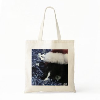 Cat in santa hat hiding in blue tinsel peering out tote bag