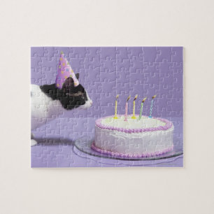 Cat wearing birthday hat blowing out candles on jigsaw puzzle