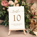 Chic Gold Script Cream Wedding Reception Table Number<br><div class="desc">Chic light cream wedding reception table number sign with "table" in an elegant gold calligraphy script with swashes, the table number in classic gold serif typography, your first names joined by a heart and your reception date. Create each table number and add to your shopping cart one at a time,...</div>