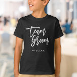 Chic Trendy Brush White Script Team Groom T-Shirt<br><div class="desc">T-shirt featuring the words "Team Groom" in chic trendy brush white script that's perfect for the ring bearer. For other matching items see here https://www.zazzle.com/collections/119250194970828530?rf=238364477188679314 Personalize it by replacing the placeholder text. For more options such as to change the font and it's size, color or the spacing between letters click...</div>