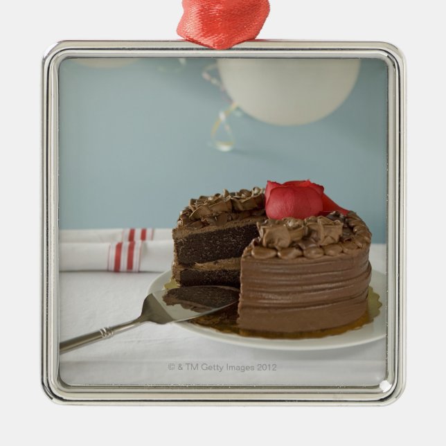 Chocolate cake with missing slice on table, metal ornament (Front)