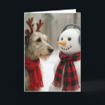 Christmas Irish Wolfhound Gazing at a Cute Snowman Card<br><div class="desc">A charming scene captures an Irish Wolfhound dog wearing reindeer antlers and a red scarf beside a snowman adorned with earmuffs and a plaid scarf,  all set against a backdrop of falling snowflakes in a wintry forest.
All text is editable.</div>