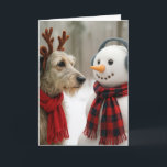 Christmas Irish Wolfhound Gazing at a Cute Snowman Card<br><div class="desc">A charming scene captures an Irish Wolfhound dog wearing reindeer antlers and a red scarf beside a snowman adorned with earmuffs and a plaid scarf,  all set against a backdrop of falling snowflakes in a wintry forest.
All text is editable.</div>