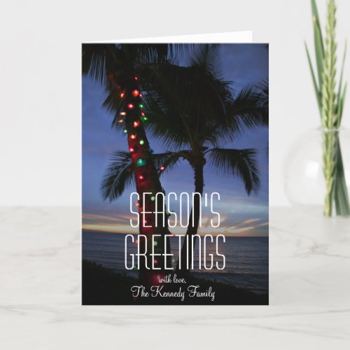 Christmas lights adorn palm tree at sunset holiday card