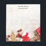 Christmas Themed Items on a Rustic Wooden Board Notepad<br><div class="desc">Personalized notepad with a rustic photograph. A light brown wooden board with various Christmas elements along the bottom. Christmas gifts,  a star,  a gold Christmas tree,  winter hat,  reindeer,  baubles and some holiday fruits.</div>