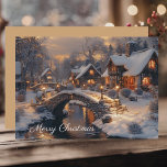 Christmas Village Vintage Winter Scene Holiday Card<br><div class="desc">A cozy Christmas holiday card featuring a watercolor illustration of a moonlit village on a snowy night with a flowing river meandering through brightly lit stone cottages and charming stone walking bridges adorned soft glowing lanterns. Merry Christmas text on the front. The reverse is a solid background color in a...</div>
